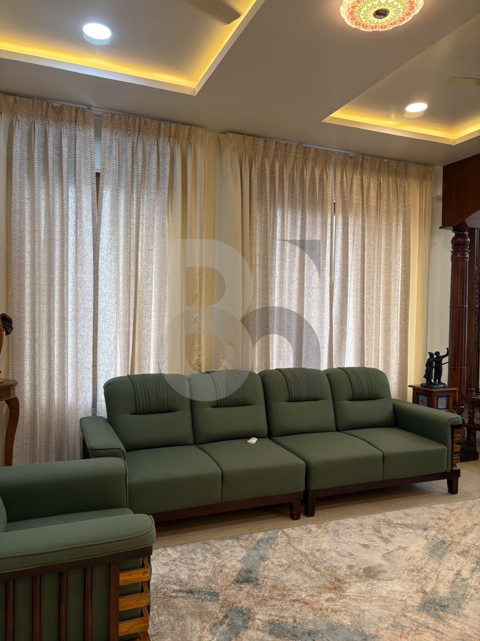 Traditional living room with olive green cushioned wood frame sofas and false ceiling by Brand Meter