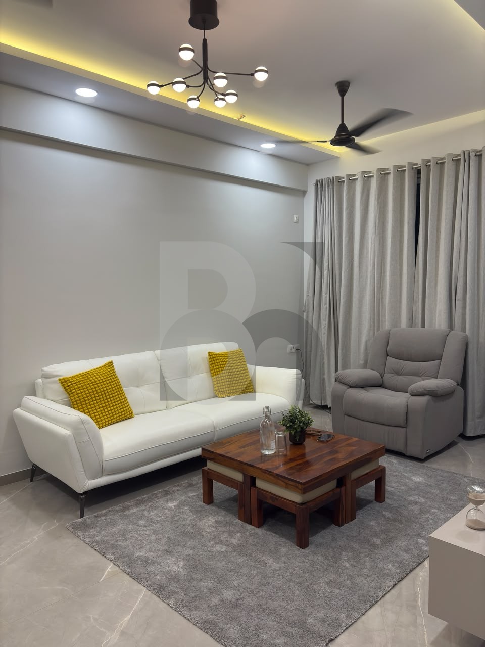 Modern living room with white leather sofa, yellow accent pillows, and branching chandelier by Brand Meter