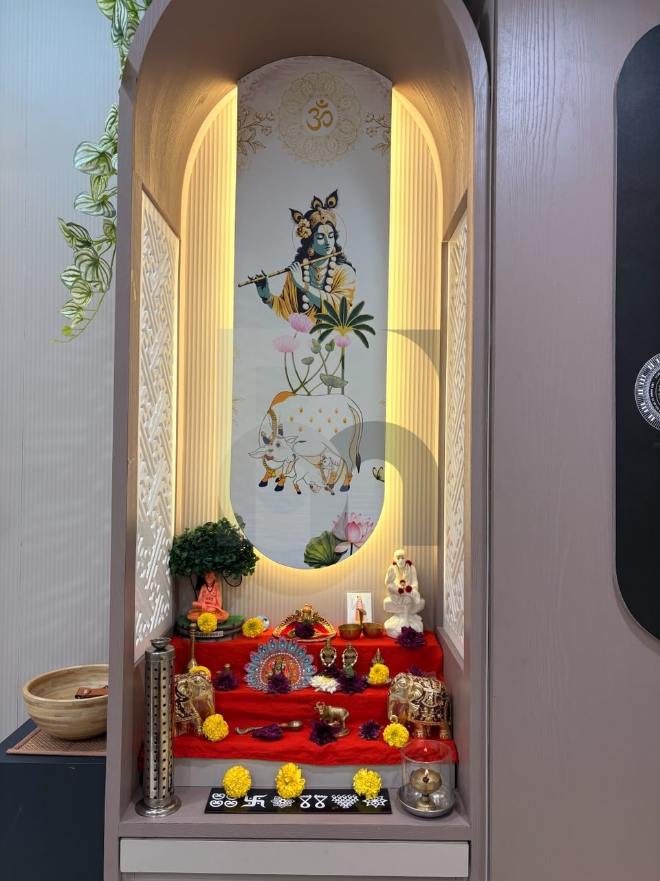 Custom home mandir pooja unit with arched niche, backlit panel, and brass statues by Brand Meter