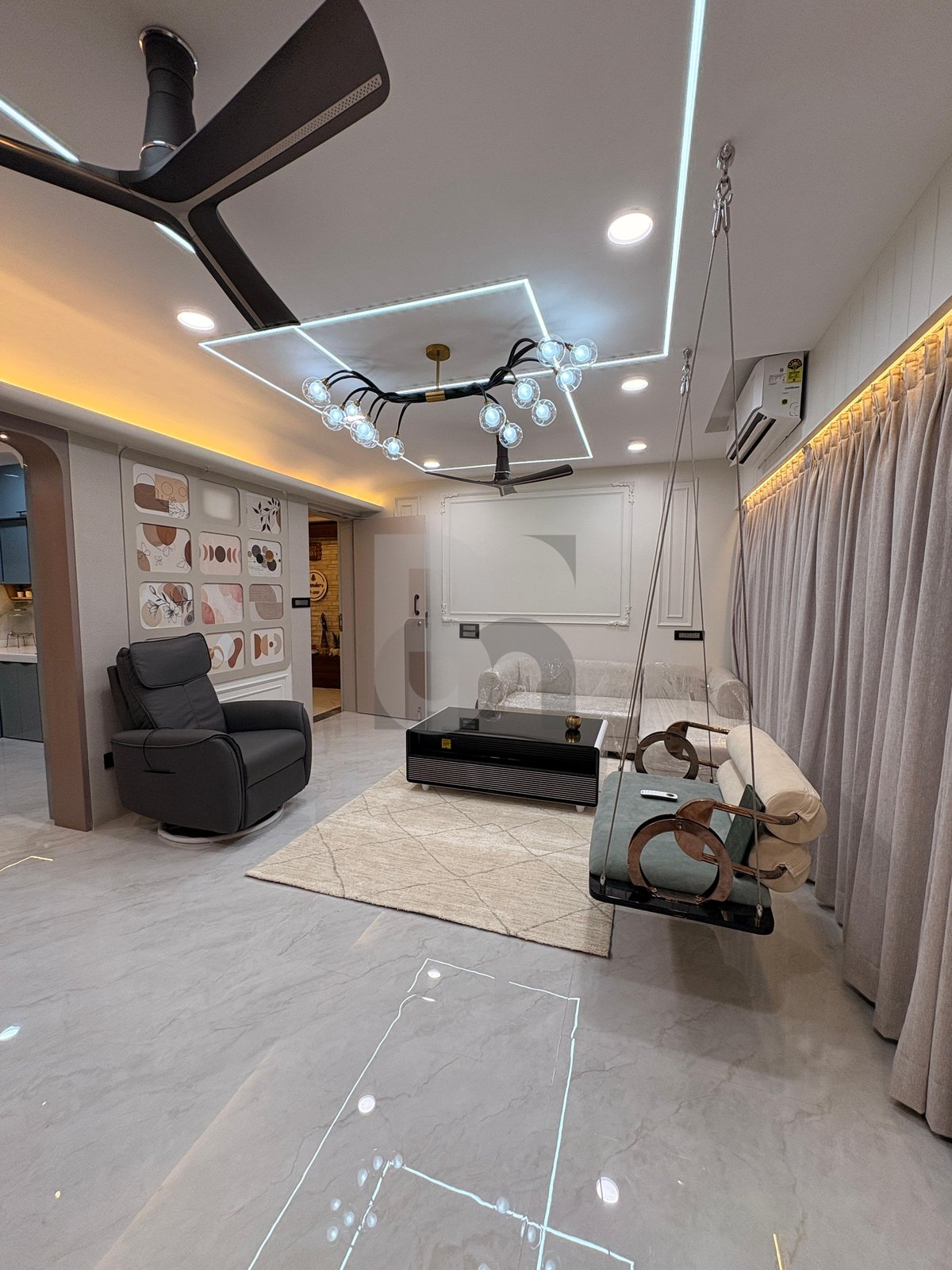 Contemporary living room featuring an elegant indoor ceiling swing, designer false ceiling, and cove lights by Brand Meter