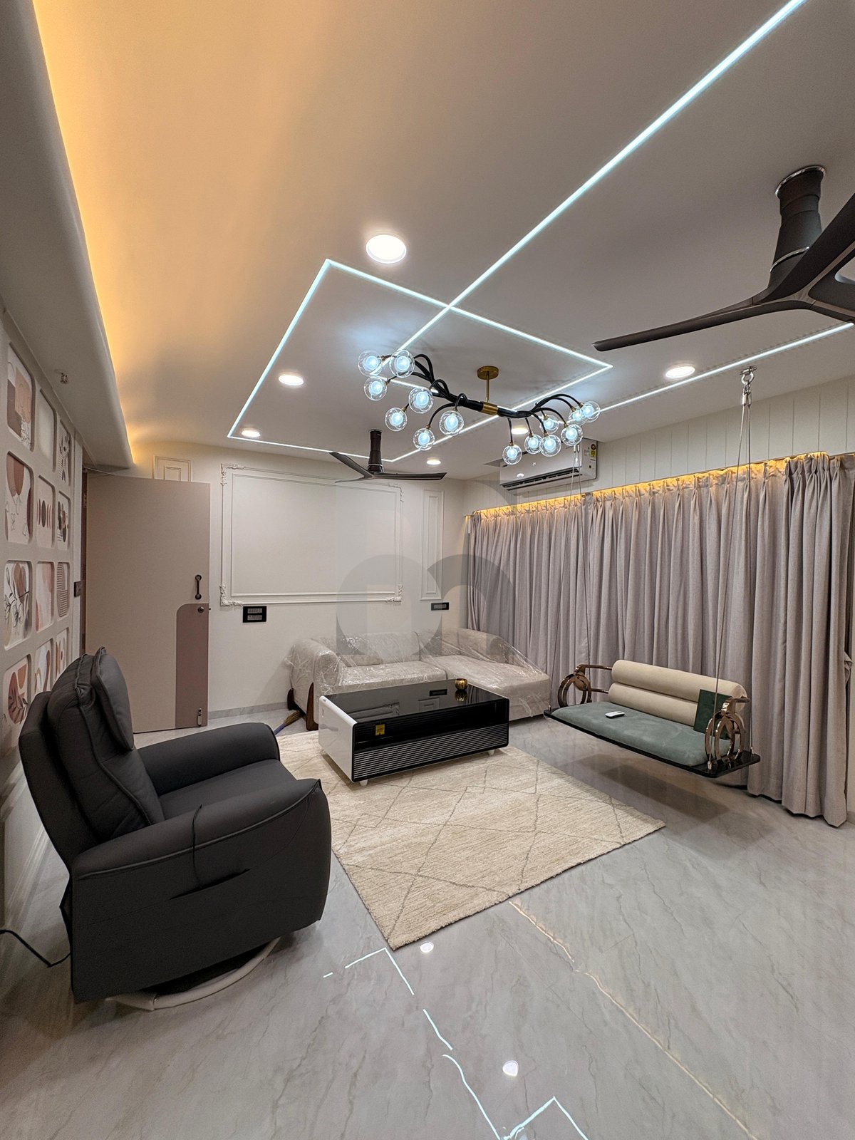 Luxury living room interior with modern chandelier, recliner chair, and open layout by Brand Meter, Vashi