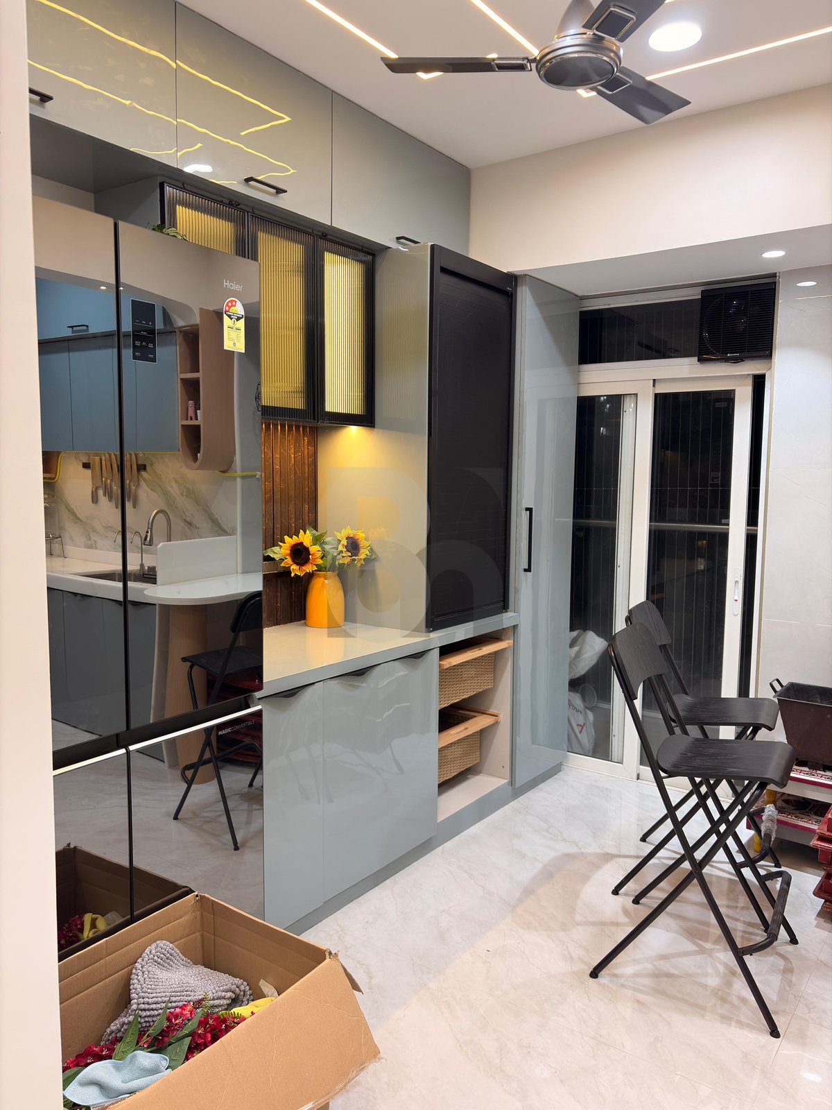 Modern modular kitchen foyer with glass bar cabinet and glossy finish pantry storage by Brand Meter