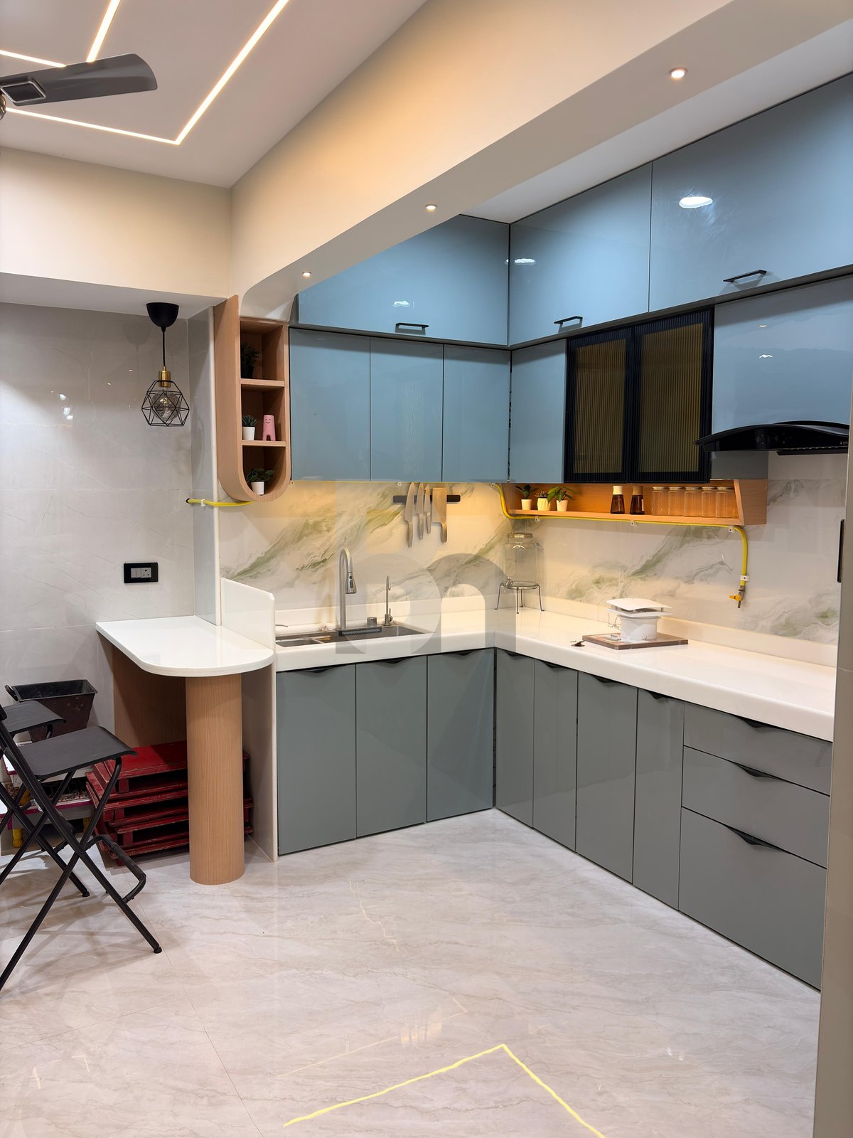 Sleek L-shaped modular kitchen with quartz countertop, breakfast bar, and pastel blue cabinetry by Brand Meter, Navi Mumbai