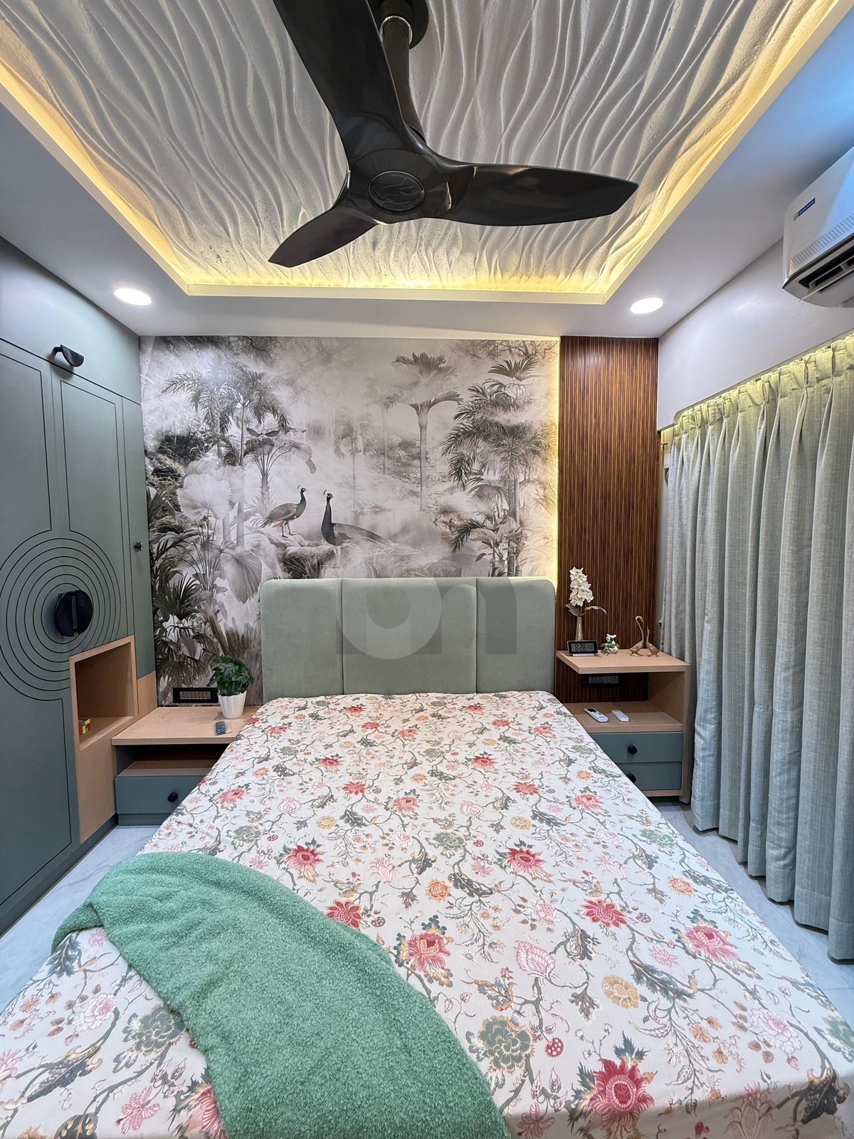 Designer bedroom featuring dramatic 3D wave false ceiling, peacock accent wallpaper, and mint headboard by Brand Meter