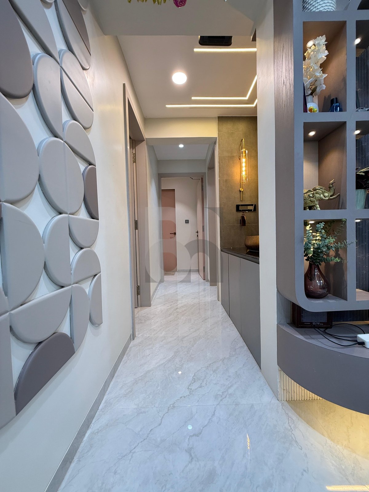 Entrance hallway corridor with 3D geometric acoustic wall panels and warm brass sconce lighting by Brand Meter